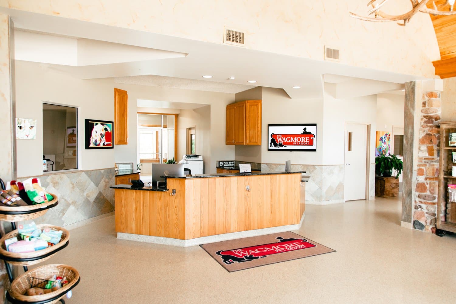 The Wagmore Pet Resort's reception lobby with the WAGMORE-branded welcome mat, retail baskets, and river-rock detail.